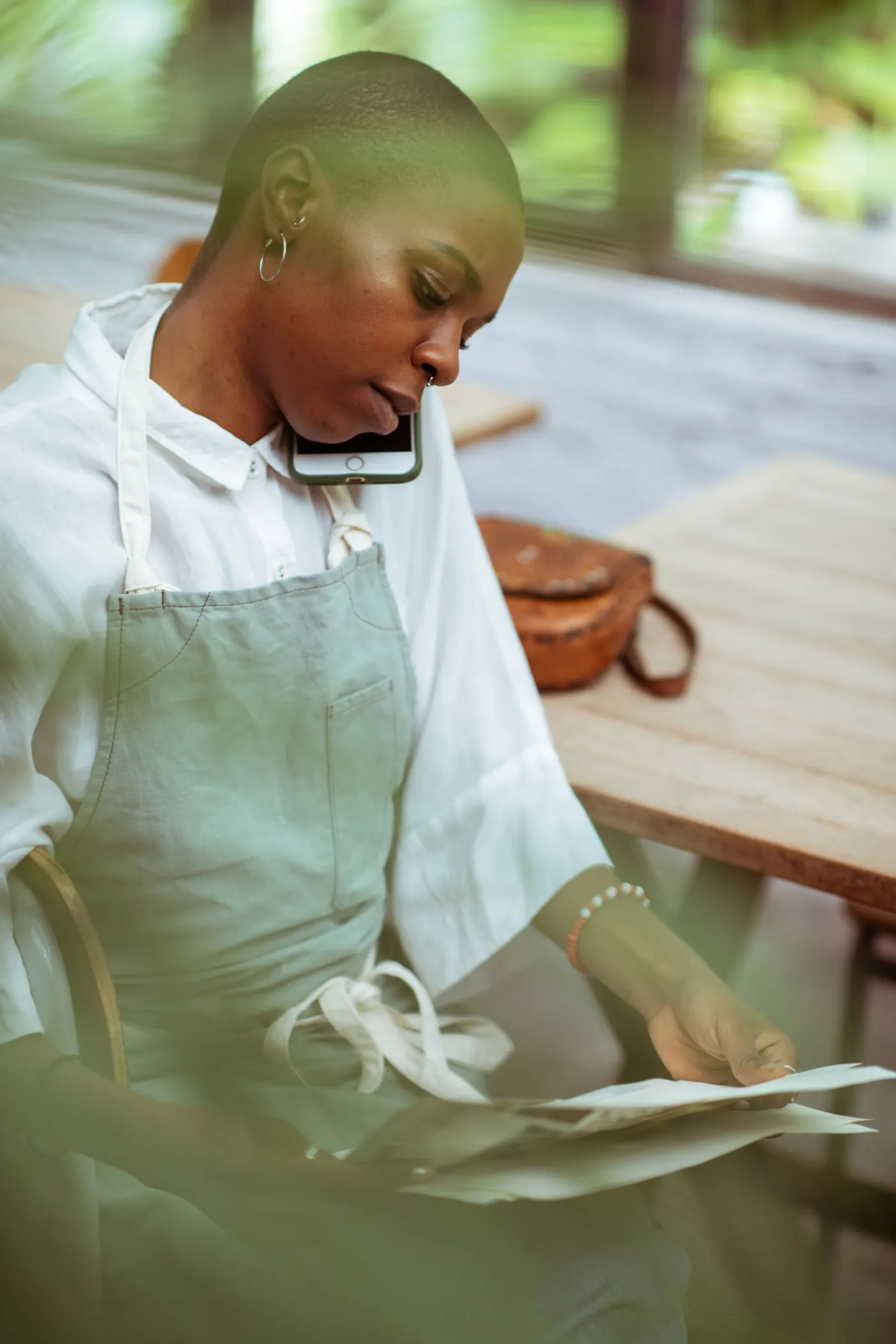 A manager in an apron on the phone, sheet in hand
