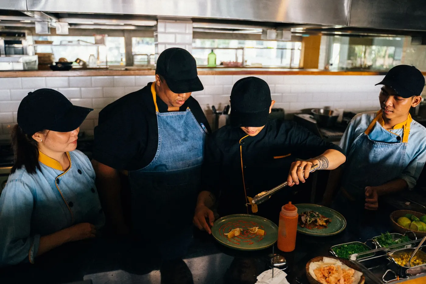 Four chefs working together at a kitchen pass