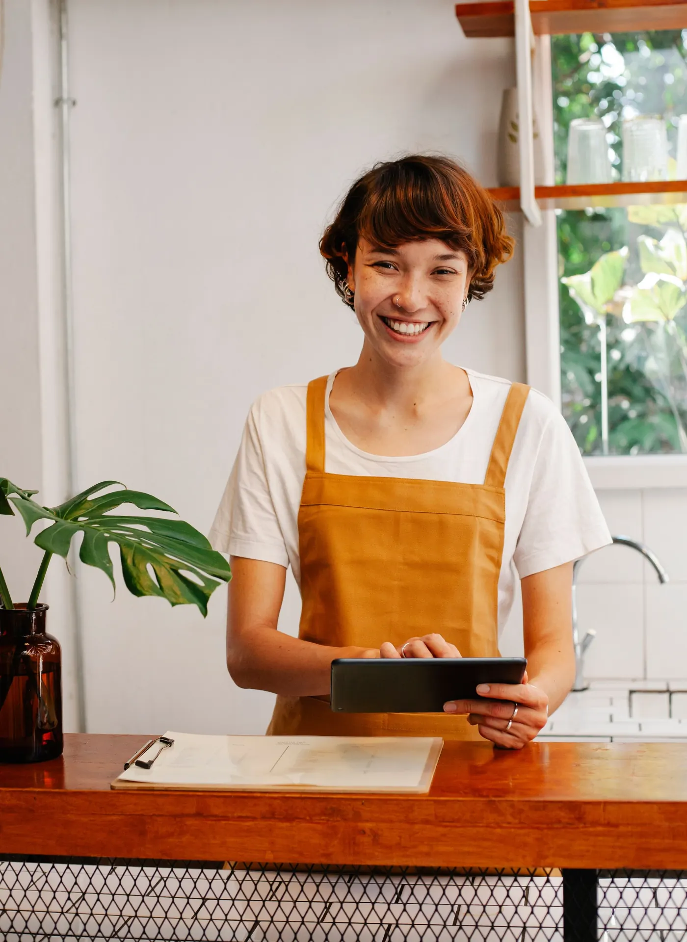 A member of staff in an apron at the counter, tablet in hand