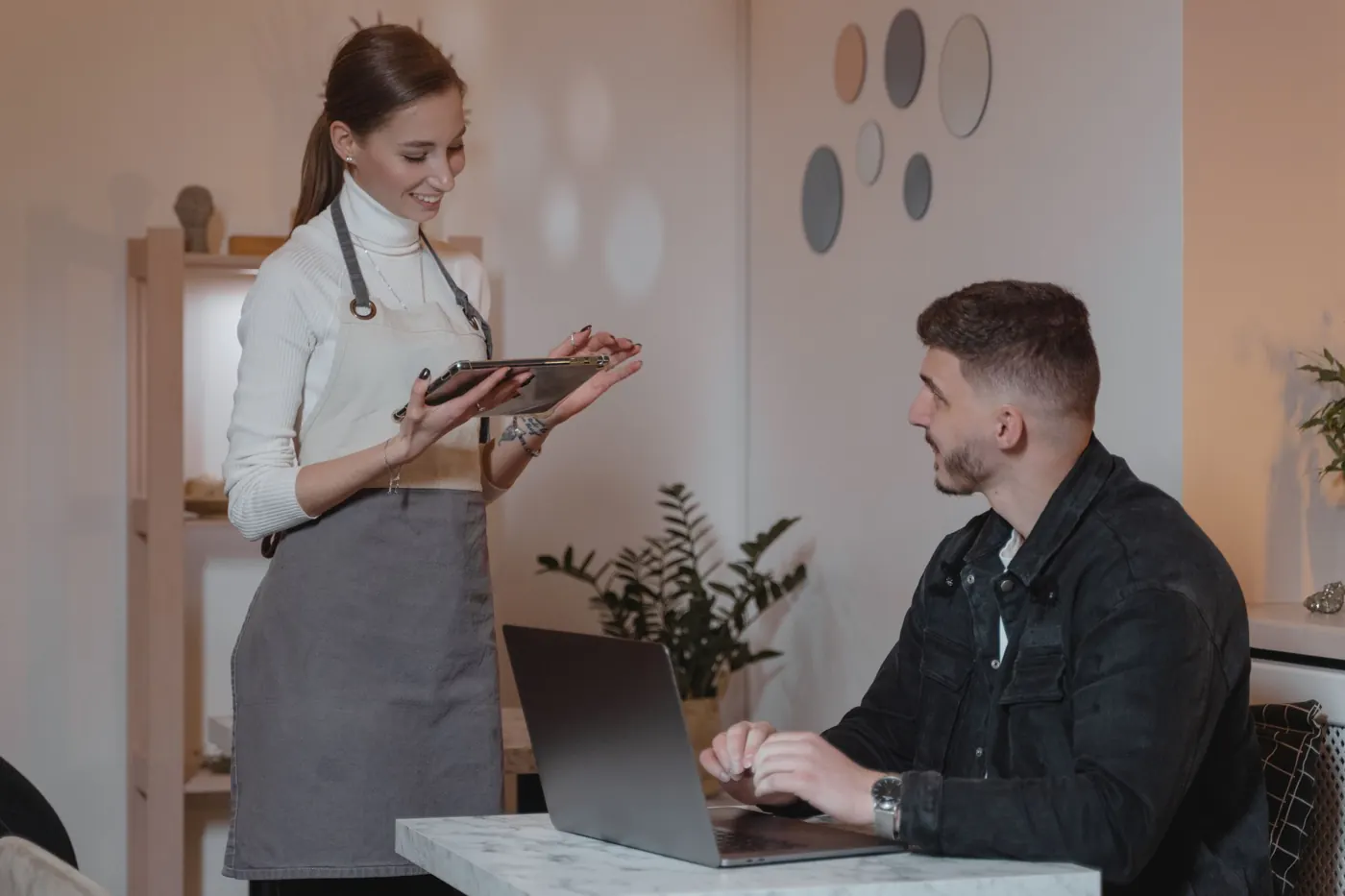 A member of staff with a tablet talking to a guest at a table